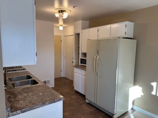 kitchen with sink, white cabinets, and white appliances