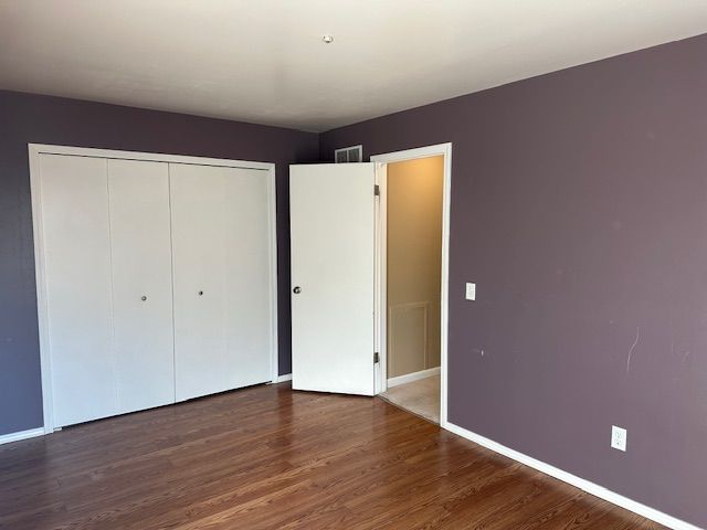 unfurnished bedroom with a closet and dark hardwood / wood-style floors