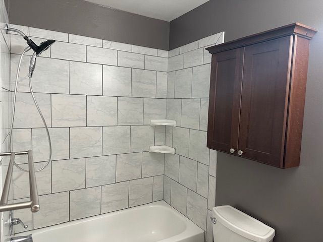 bathroom featuring tiled shower / bath combo and toilet