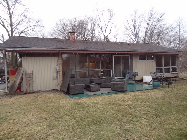 rear view of property featuring outdoor lounge area, a lawn, and a sunroom