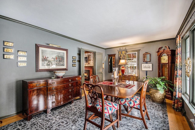 dining space featuring hardwood / wood-style flooring, ornamental molding, and a brick fireplace