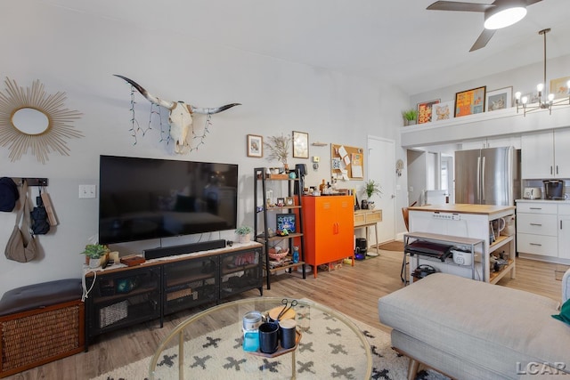 living room with ceiling fan with notable chandelier and light wood-type flooring