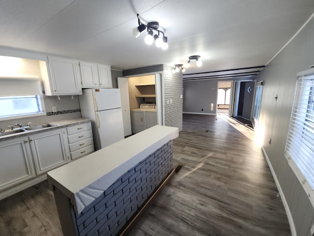 kitchen with sink, washer and dryer, dark hardwood / wood-style floors, white fridge, and white cabinets