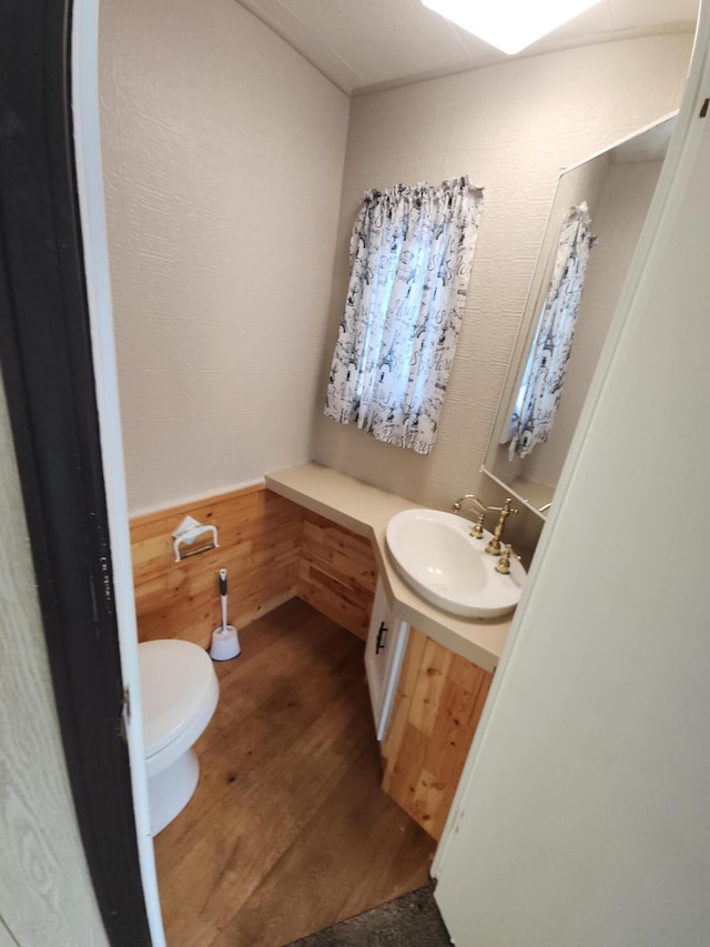 bathroom featuring hardwood / wood-style flooring, vanity, toilet, and wood walls