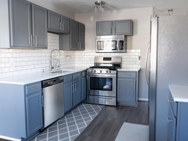 kitchen with tasteful backsplash, appliances with stainless steel finishes, sink, and dark wood-type flooring