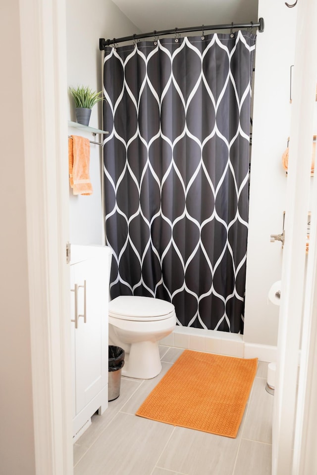 bathroom with tile patterned flooring, toilet, and walk in shower