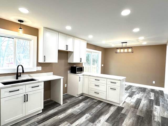 kitchen featuring hanging light fixtures, sink, white cabinets, and kitchen peninsula