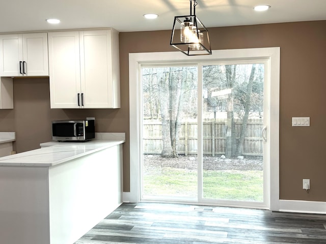 kitchen with pendant lighting, white cabinetry, light stone countertops, and hardwood / wood-style floors