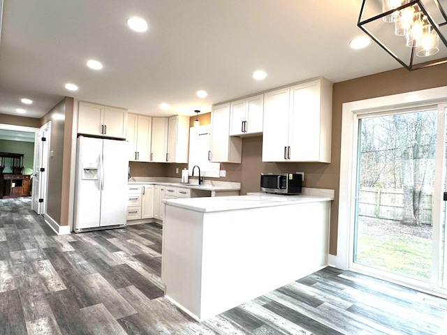 kitchen with sink, white cabinets, dark hardwood / wood-style flooring, white refrigerator with ice dispenser, and kitchen peninsula