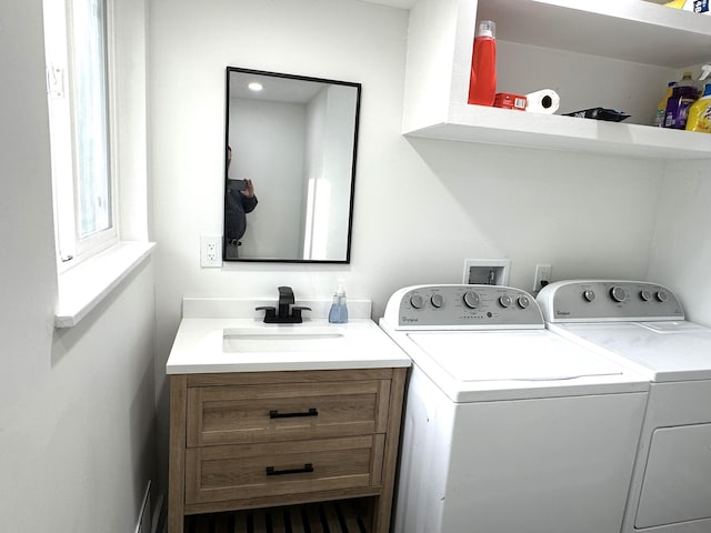 washroom with cabinets, washing machine and clothes dryer, and sink