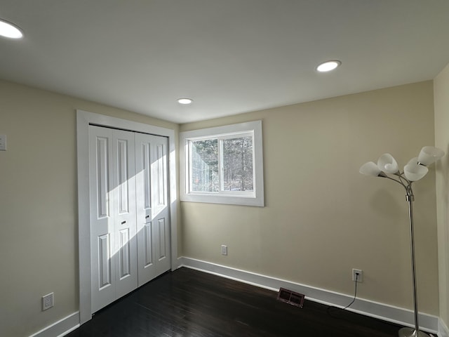 unfurnished bedroom with dark hardwood / wood-style floors and a closet