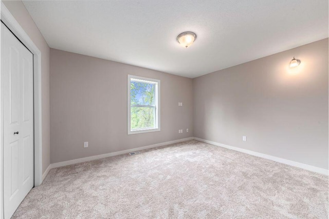 unfurnished bedroom featuring a closet and light carpet