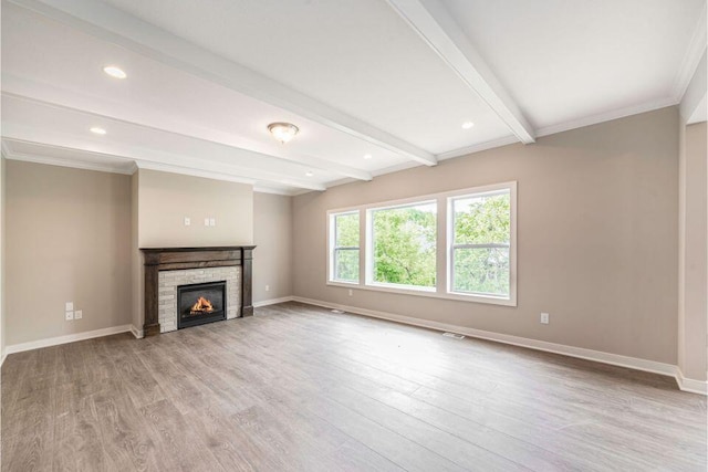 unfurnished living room featuring beamed ceiling, crown molding, and light wood-type flooring