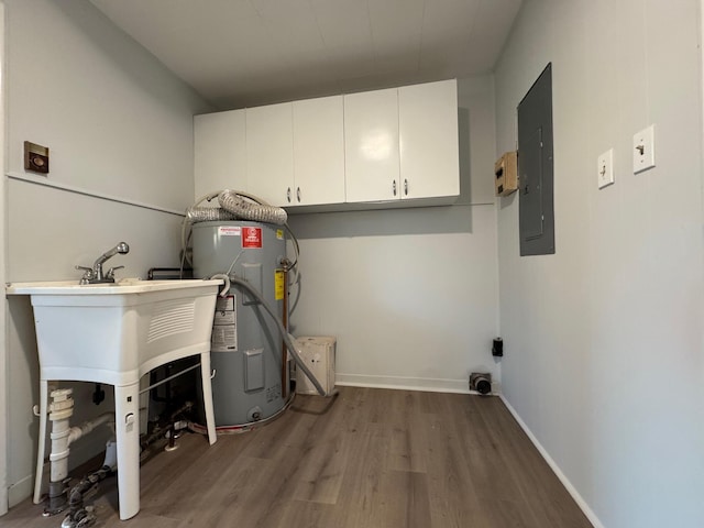 washroom with hardwood / wood-style flooring, water heater, electric dryer hookup, electric panel, and cabinets