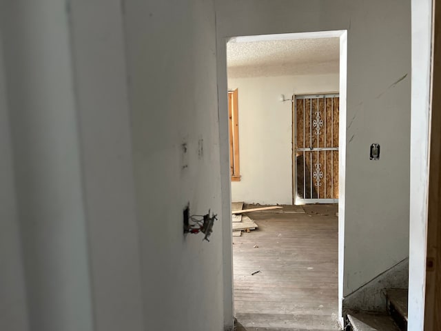 hallway with hardwood / wood-style floors and a textured ceiling