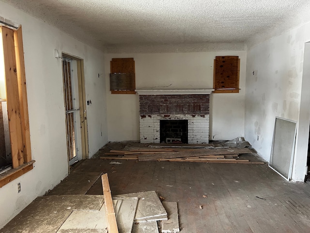 unfurnished living room featuring a brick fireplace and a textured ceiling