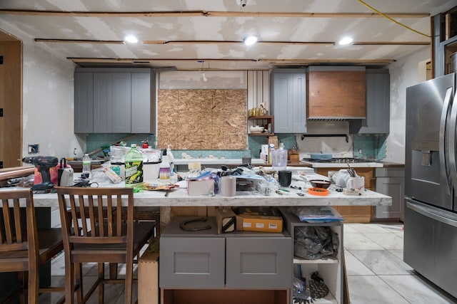 kitchen with light tile patterned floors, gray cabinets, backsplash, a kitchen breakfast bar, and stainless steel fridge with ice dispenser