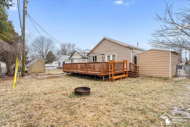 back of house with a storage unit, a yard, a deck, and a fire pit