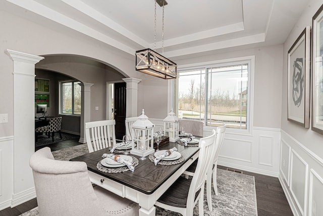 53188 Woodland Mdws, Chesterfield, MI 48047 - dining area with decorative columns, arched walkways, wainscoting, dark wood-type flooring, and a tray ceiling