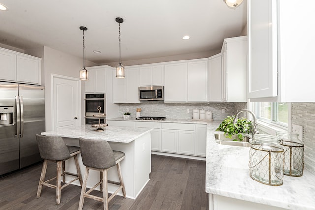 53188 Woodland Mdws, Chesterfield, MI 48047 - kitchen with stainless steel appliances, decorative backsplash, white cabinetry, a sink, and a kitchen island