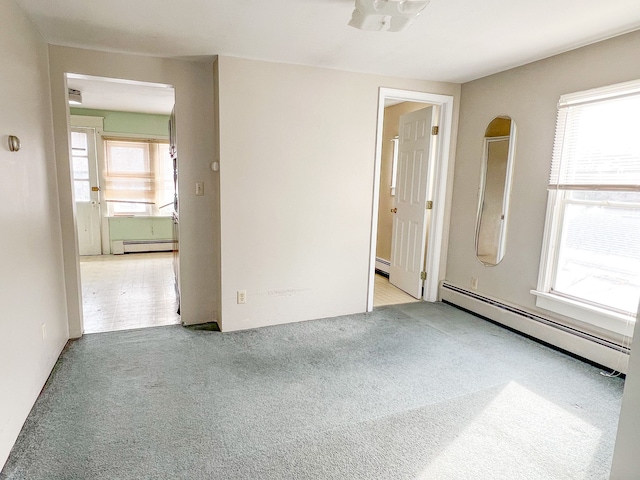 spare room with a baseboard radiator, light colored carpet, and a healthy amount of sunlight