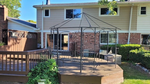 rear view of property with a deck and brick siding
