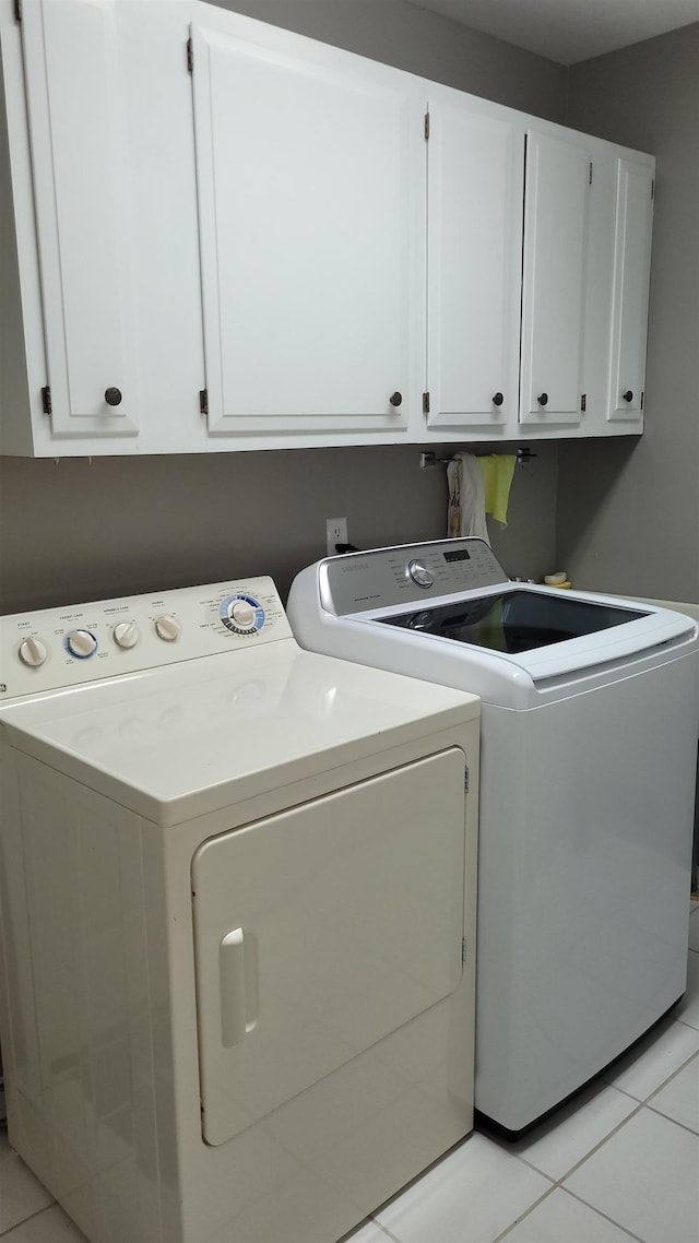 washroom with separate washer and dryer, cabinet space, and light tile patterned floors
