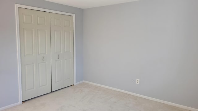 unfurnished bedroom featuring light carpet and a closet