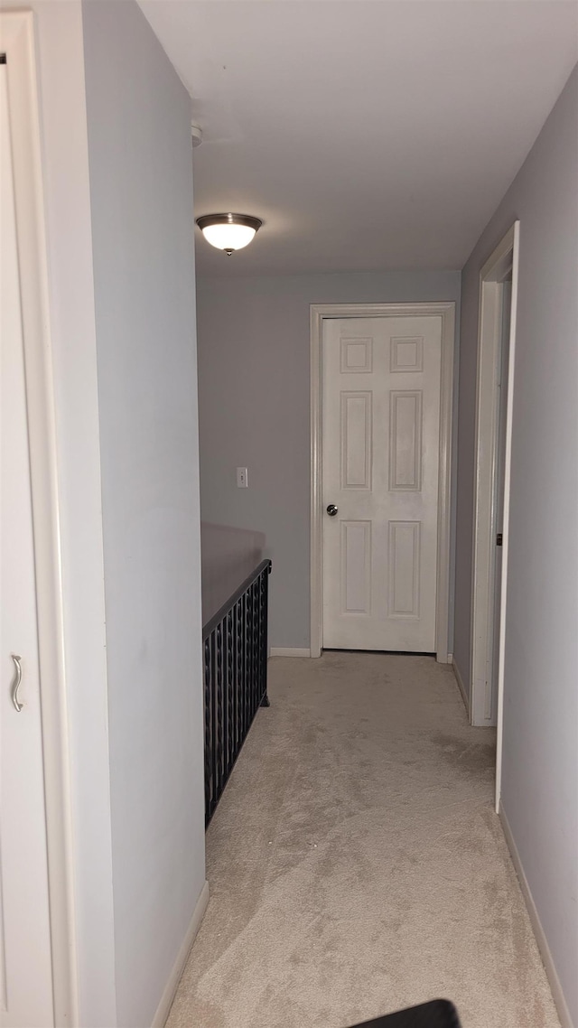 hall with light colored carpet and baseboards