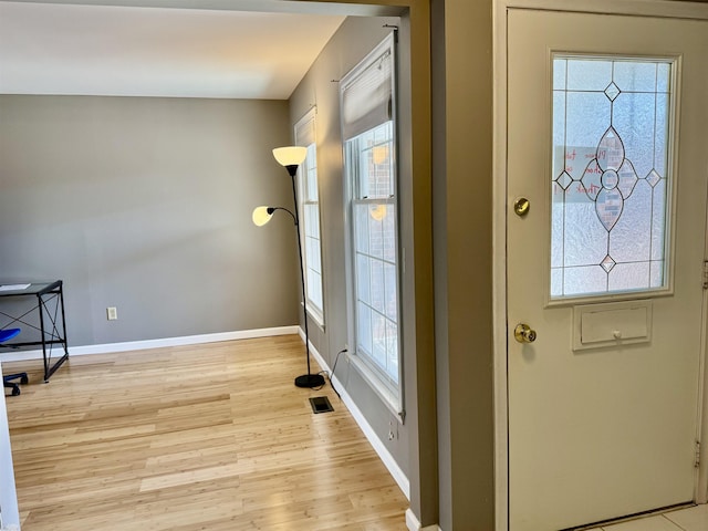 doorway with light wood finished floors, baseboards, and plenty of natural light