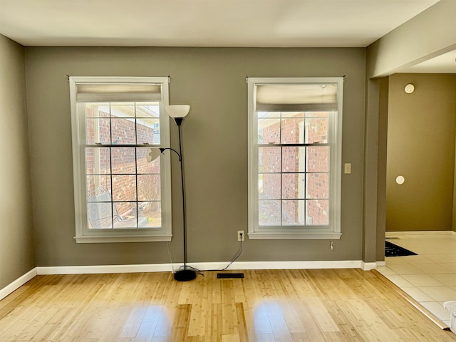 unfurnished dining area featuring wood-type flooring, healthy amount of natural light, and baseboards