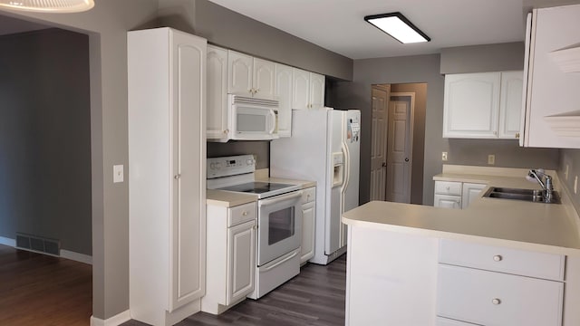 kitchen with sink, white appliances, white cabinetry, dark hardwood / wood-style flooring, and kitchen peninsula