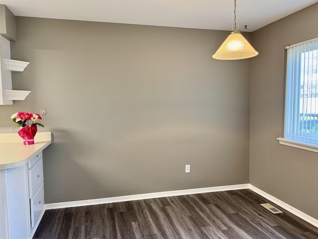 unfurnished dining area with dark wood-style floors and baseboards