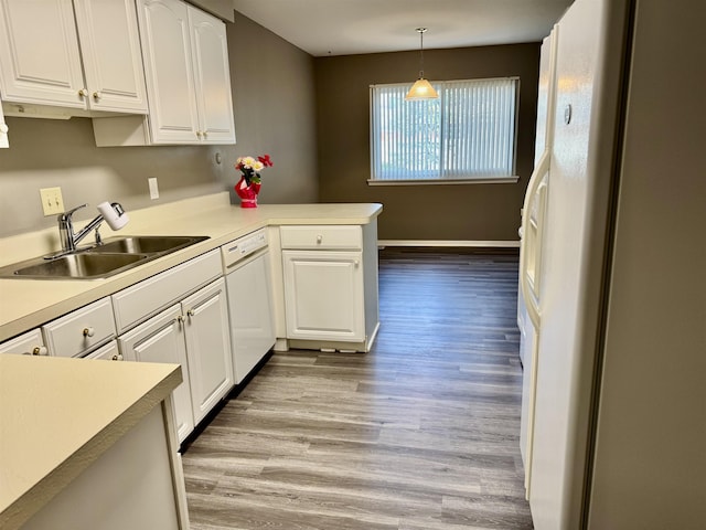 kitchen with white appliances, a sink, white cabinets, and a peninsula