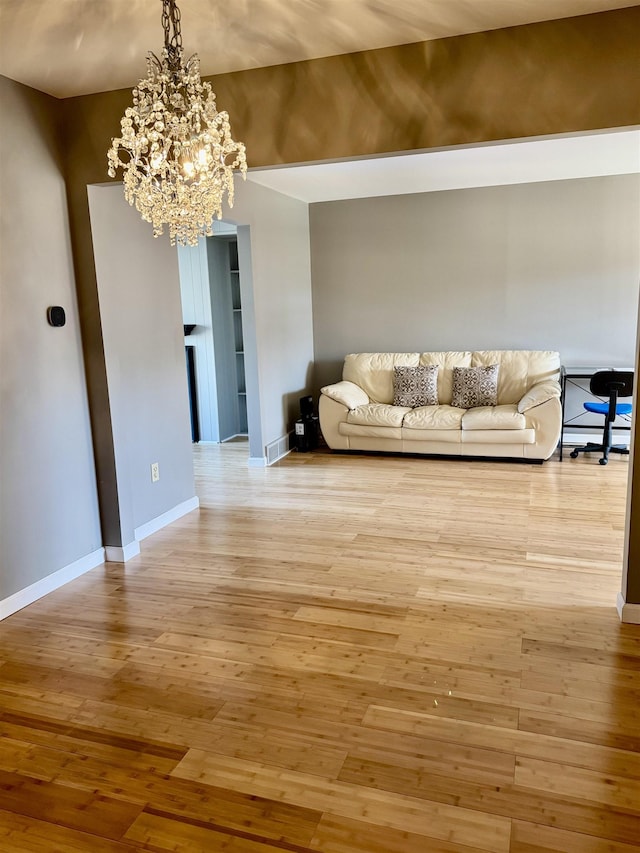 living area featuring baseboards, a chandelier, wood-type flooring, built in shelves, and baseboard heating