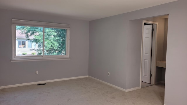 spare room with light colored carpet and baseboards
