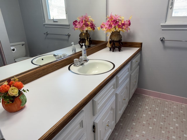 bathroom with vanity, tile patterned floors, baseboards, and toilet