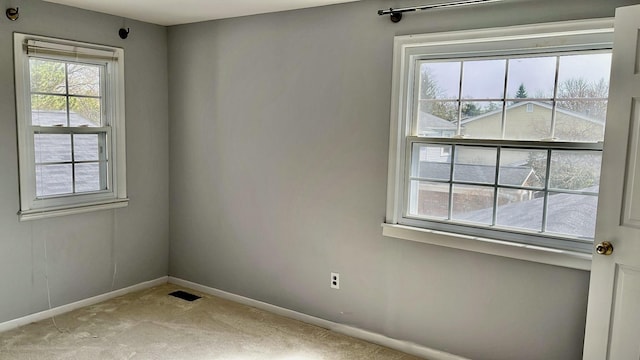 unfurnished room featuring light carpet and baseboards