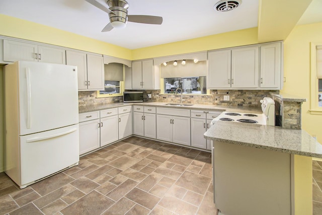 kitchen with sink, white appliances, kitchen peninsula, and white cabinets