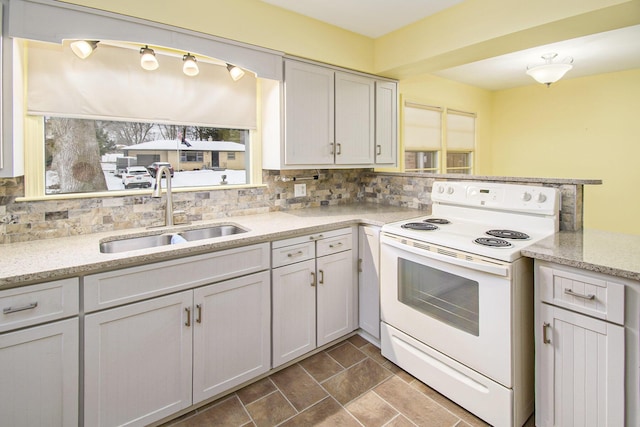 kitchen with tasteful backsplash, sink, white electric stove, and light stone countertops