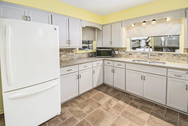 kitchen featuring sink, decorative backsplash, and white refrigerator