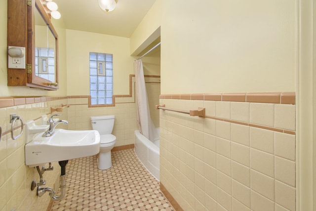 full bathroom featuring toilet, shower / bathtub combination with curtain, sink, and tile walls