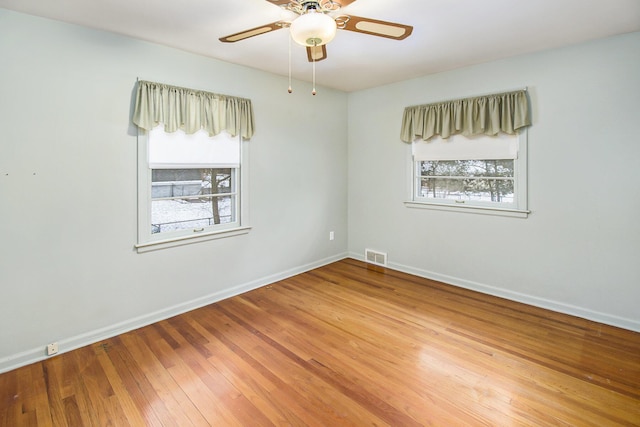 empty room featuring wood-type flooring, a healthy amount of sunlight, and ceiling fan