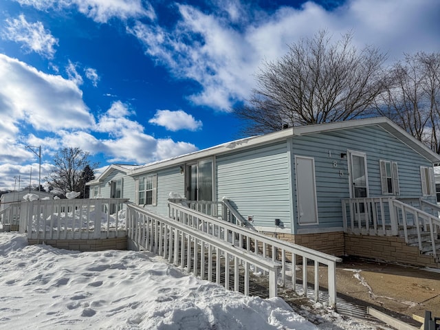 snow covered back of property featuring a wooden deck