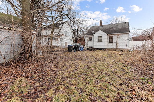 back of house featuring a chimney and fence