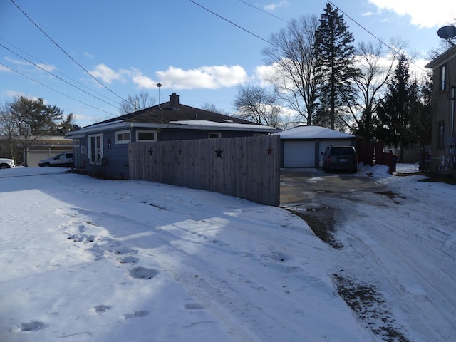 snow covered property with an outbuilding and a detached garage