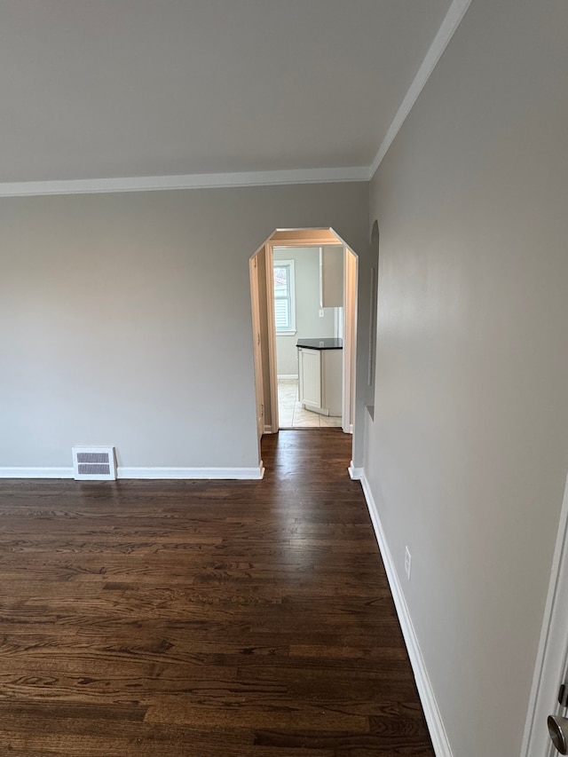 spare room with dark wood-type flooring and ornamental molding