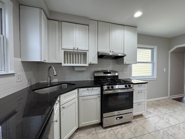 kitchen featuring gas range, sink, dark stone countertops, and white cabinets