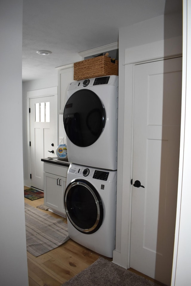 laundry room featuring hardwood / wood-style flooring and stacked washer and clothes dryer