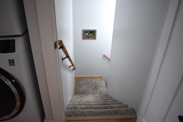 stairs featuring stacked washer / drying machine